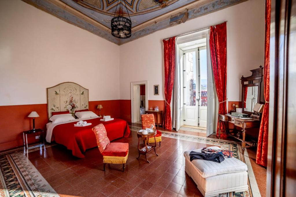 1 dormitorio con cama roja, mesa y sillas en Dimora Storica Giostra Vecchia - Palazzo Grisolia 1809 en Cosenza