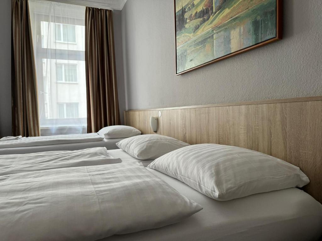 a hotel room with two beds with white pillows at Hotel Kieler Hof am Hauptbahnhof - Hamburg Central Station in Hamburg