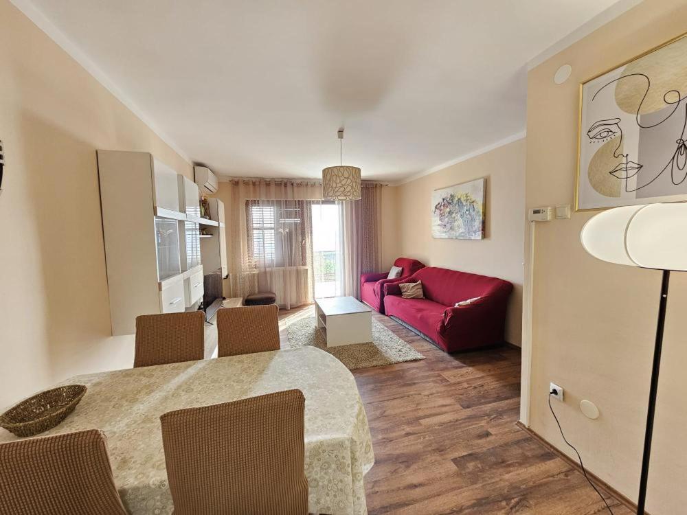 Dj apartment Kostrena في Šodići: غرفة معيشة مع طاولة وأريكة حمراء