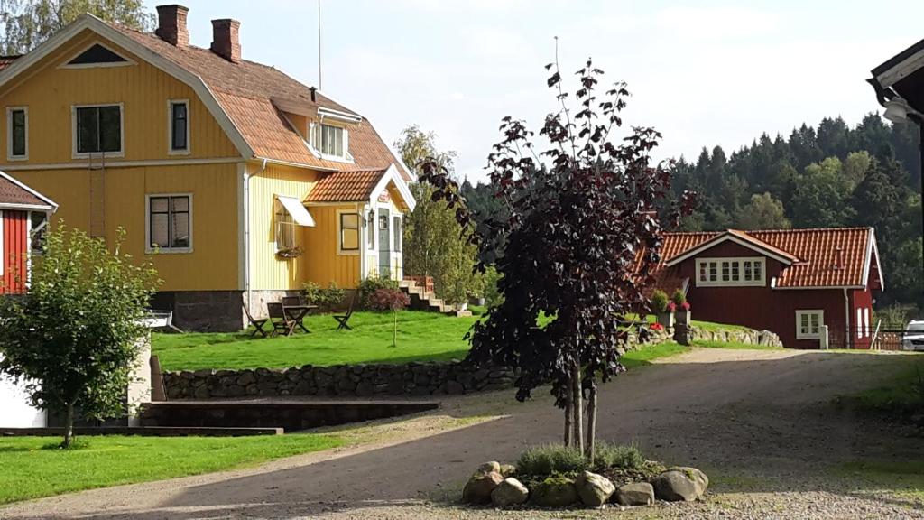 a yellow house with a tree in the middle of a road at Älgbergets Bed & Breakfast in Ucklum