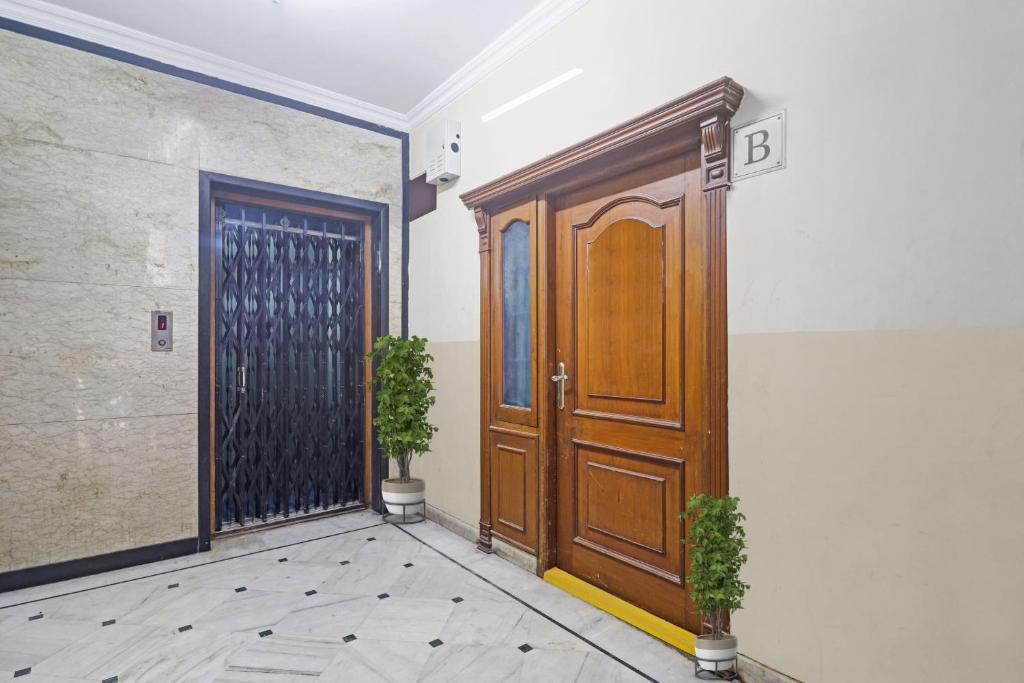 an empty hallway with a wooden door and potted plants at Capital O Hotel Samrat Palace Near Nampally Station in Hyderabad