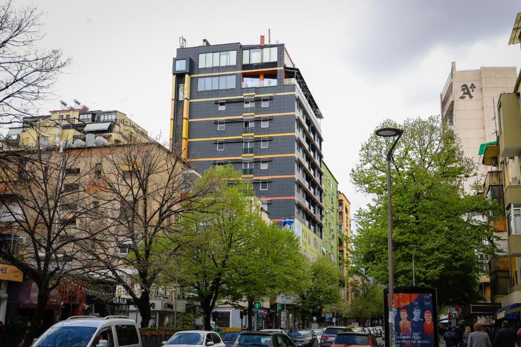 un edificio alto en una calle de la ciudad con coches en La Bohème Hotel, en Tirana