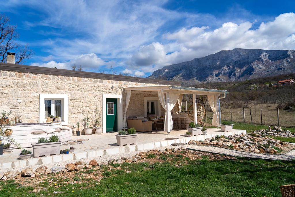 une maison en pierre avec une pergola dans une cour dans l'établissement Stone House With Jacuzzi "DINARA", à Kijevo