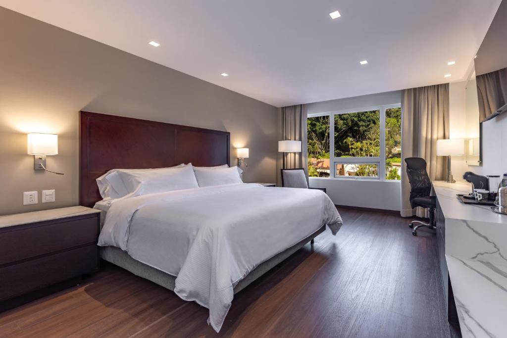 ein Schlafzimmer mit einem großen weißen Bett und einem Fenster in der Unterkunft Hotel Biltmore in Guatemala
