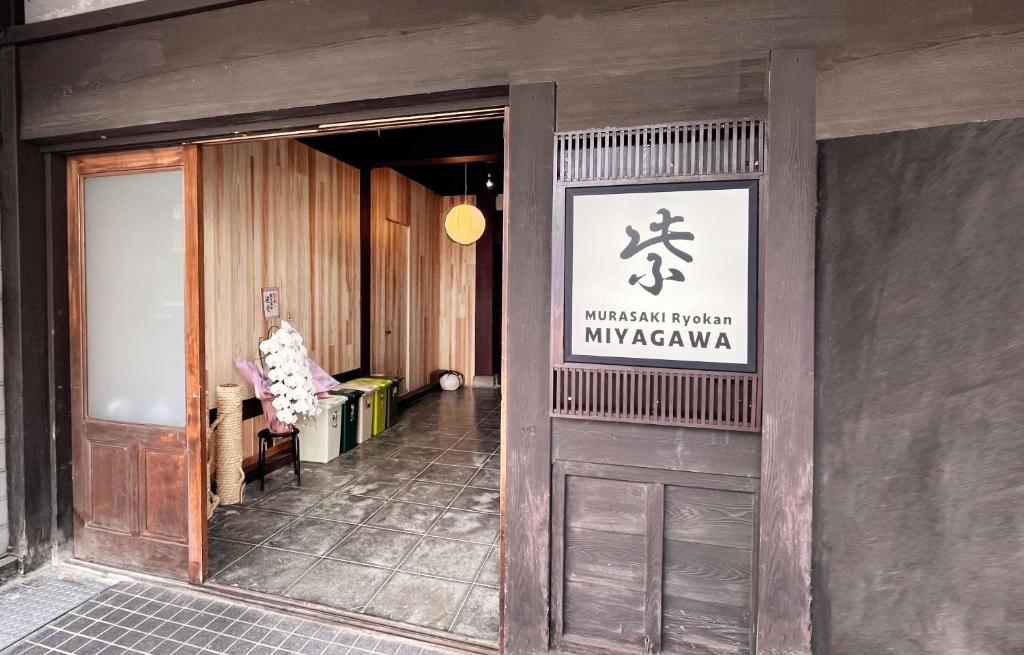 a entrance to a building with a sign on the door at Hostel Murasaki Ryokan Miyagawa in Takayama