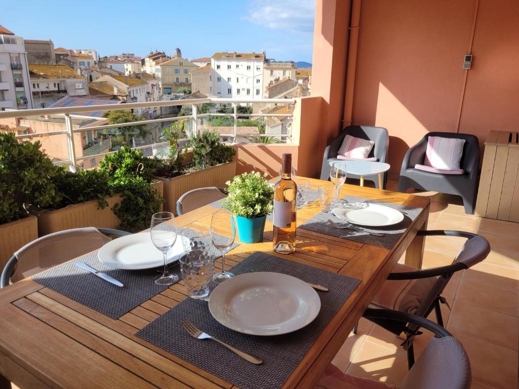 une table avec des assiettes et des verres à vin sur un balcon dans l'établissement Bel appartement 2 chambres proche plage et golfs by Beds83, à Saint-Raphaël