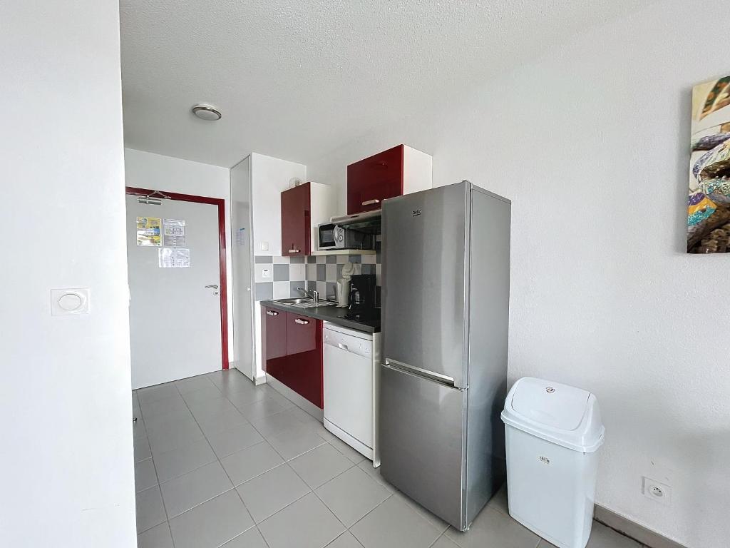 La cuisine est équipée de placards rouges et d'un réfrigérateur en acier inoxydable. dans l'établissement 3311-T3 résidence avec piscine, à Argelès-sur-Mer