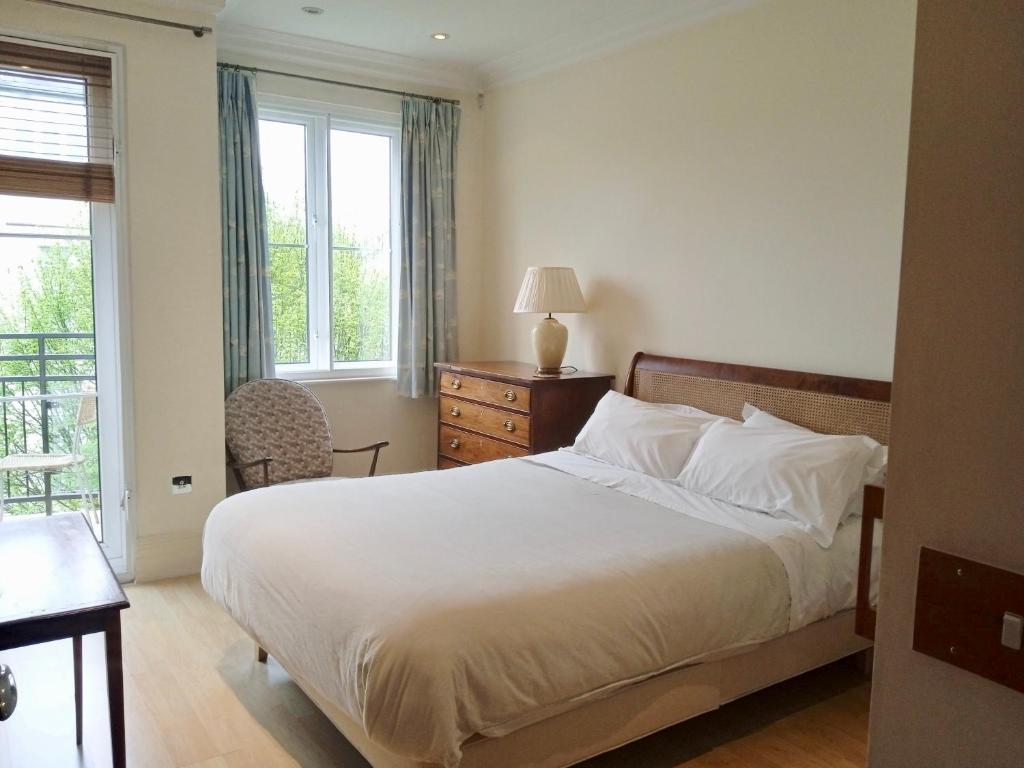 a bedroom with a bed and a desk and window at Luxury apartment London Kew National Archives in London