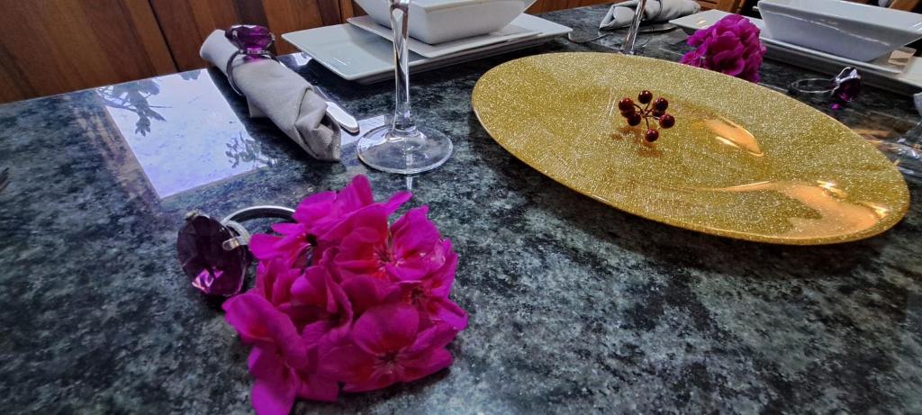 einen Tisch mit einer goldenen Platte und lila Blumen darauf in der Unterkunft The Palm Villa in St Paul's Bay