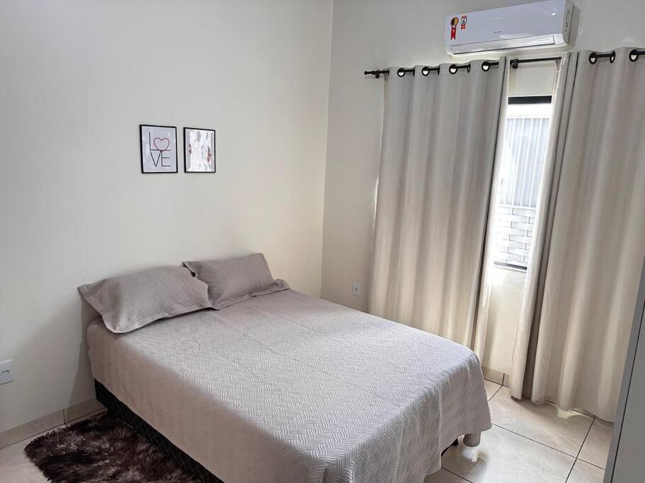ein weißes Schlafzimmer mit einem Bett und einem Fenster in der Unterkunft Casa bem localizado em Sinop in Sinop