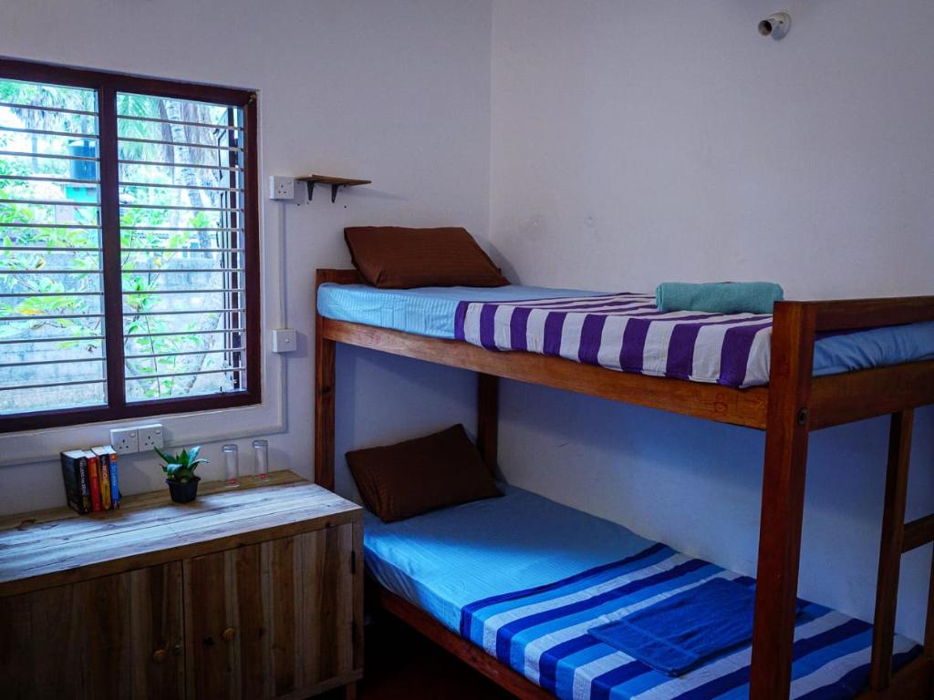 2 łóżka piętrowe w pokoju z oknem w obiekcie The White House w mieście Trikunamalaja
