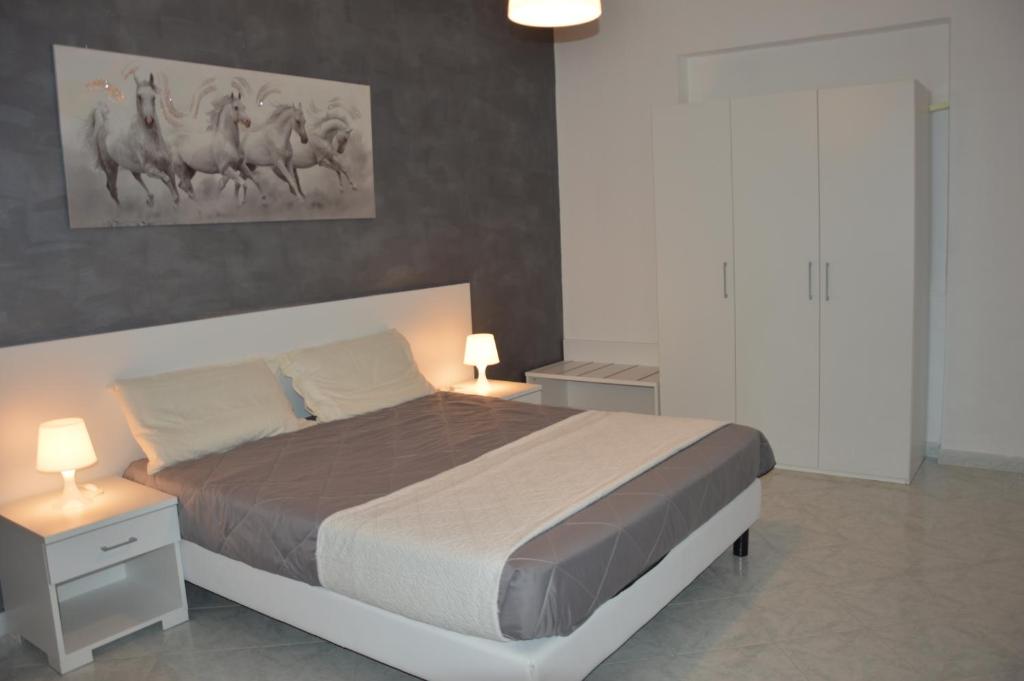 a bedroom with a large bed with two tables and two lamps at Helios Rooms in Flumini di Quartu