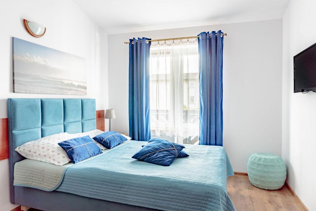 a bedroom with a blue bed with blue curtains at Pokoje Gościnne Miła 12 - Bardzo Blisko Plaży in Karwia