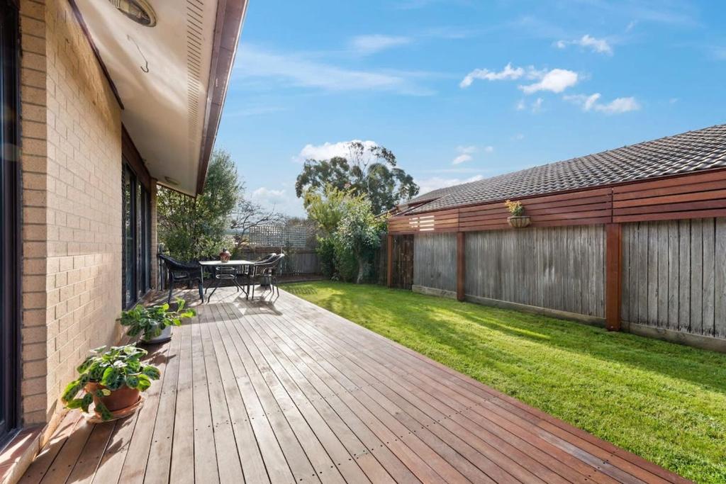 a backyard with a wooden deck and grass at Awesome family House & Studio in Narrabundah