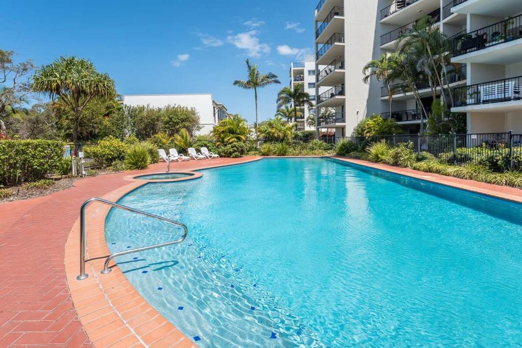 uma piscina em frente a um edifício de apartamentos em Beachfront Oasis with Private Rooftop Retreat em Marcoola