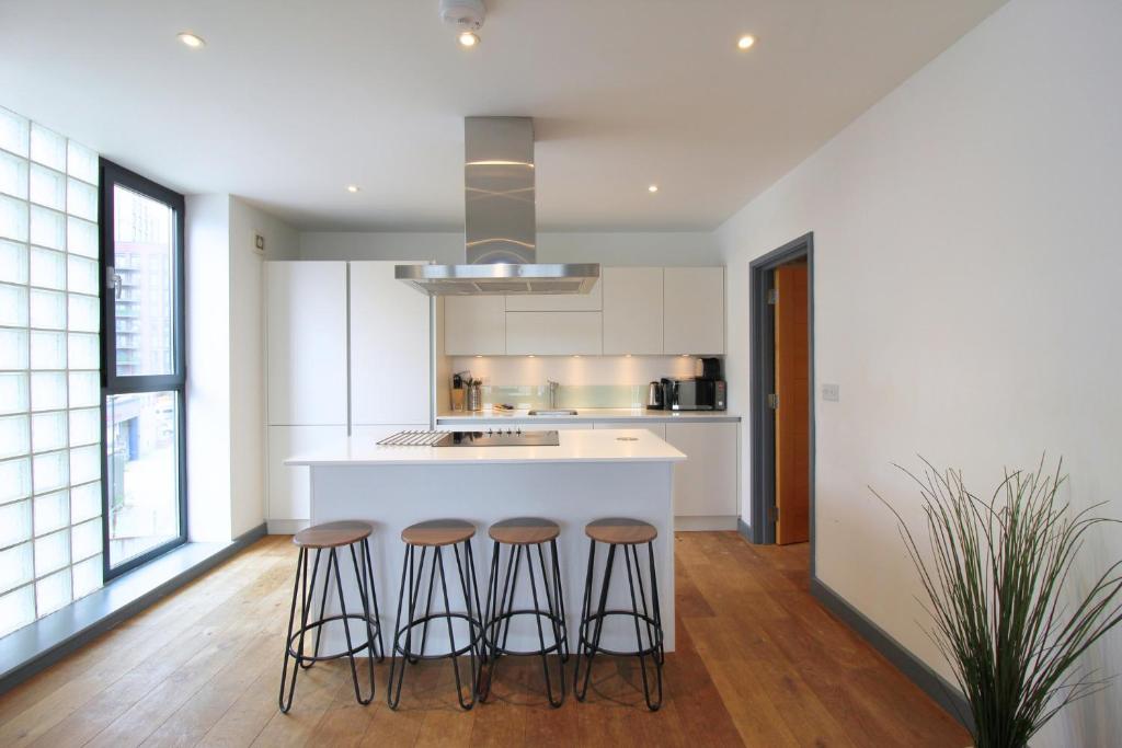 a kitchen with three bar stools and a counter at Canning Town by Viridian Apartments in London