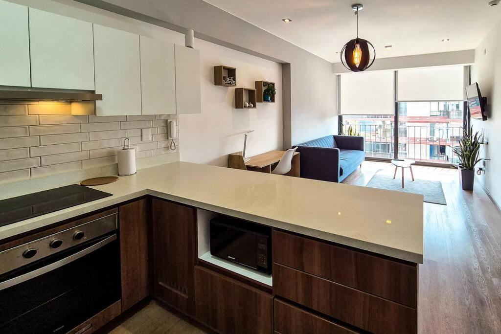 a kitchen with a counter top and a living room at Lujoso Apartamento Ejecutivo en centro San Isidro in Lima