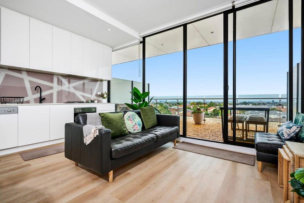 a living room with a black couch and a kitchen at Stylish Urban Retreat with Spectacular Views and Prime Location in Melbourne