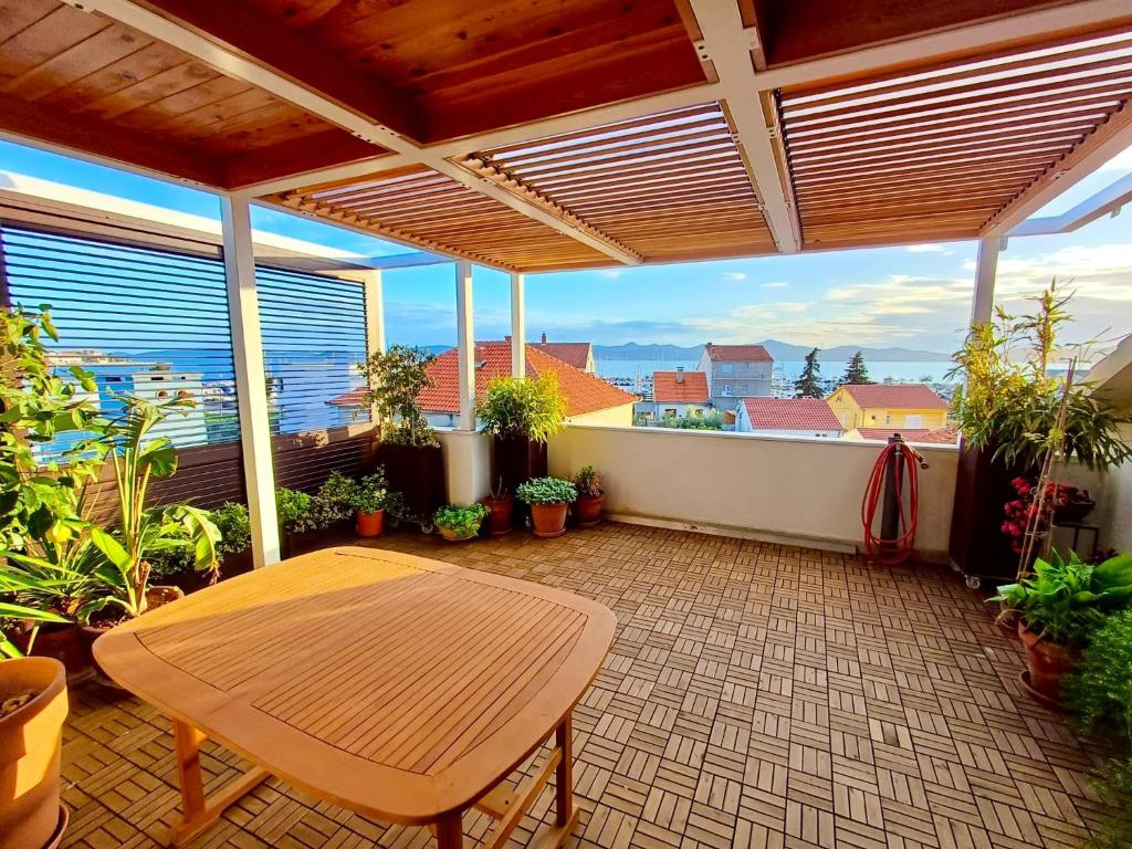 eine Terrasse mit einem Holztisch und einigen Pflanzen in der Unterkunft Apartments Babin in Zadar