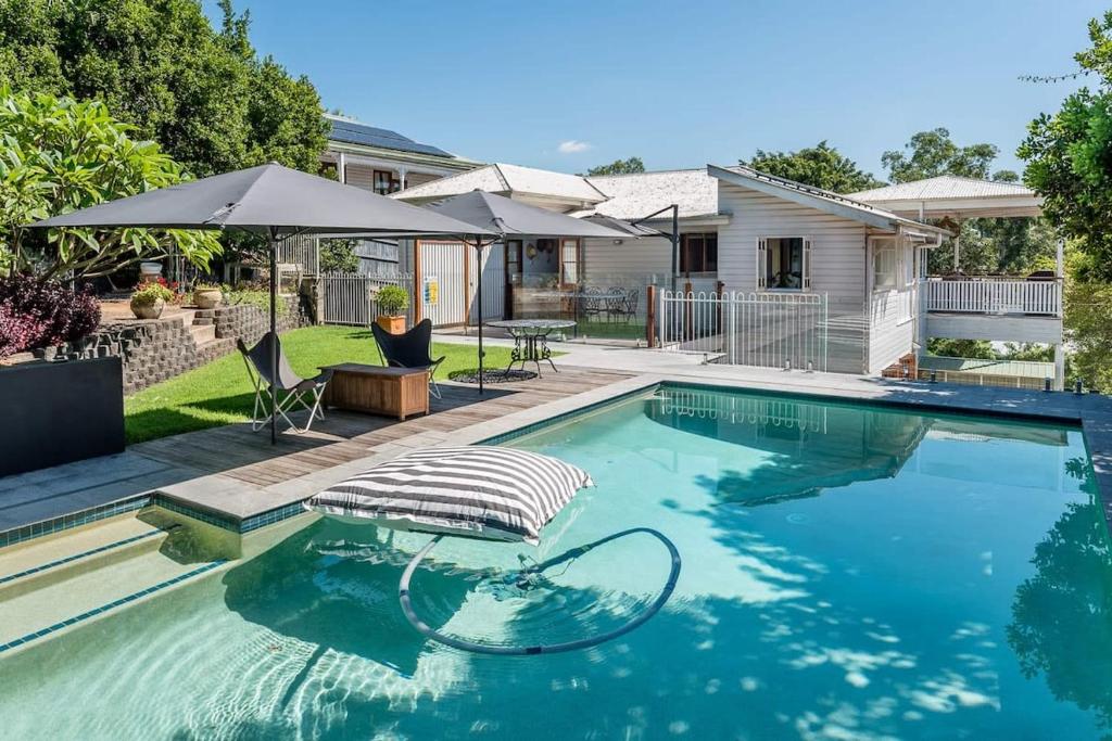 uma piscina com um guarda-sol e uma casa em Homely Hideaway Bardon em Brisbane