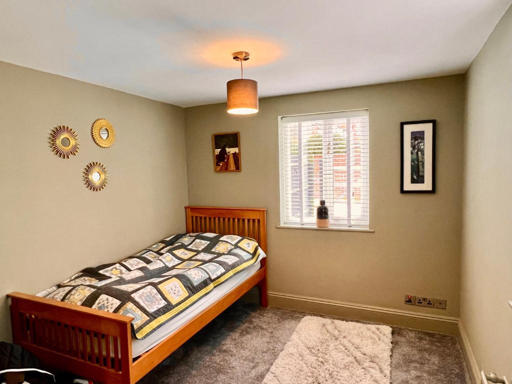 a bedroom with a bed and a window at Historic & Stylish Cottage in Charlton Kings