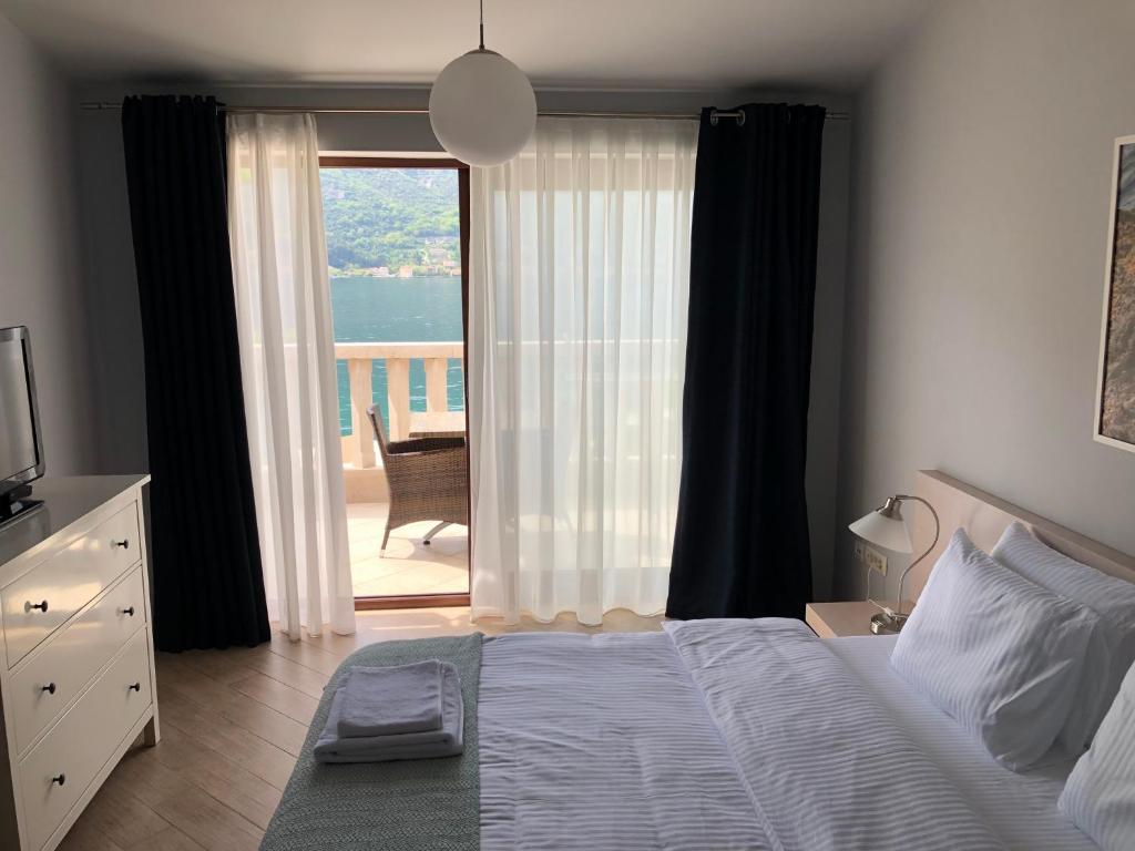 1 dormitorio con cama y vistas a un balcón en Turquoise Beachside Apartments en Dobrota