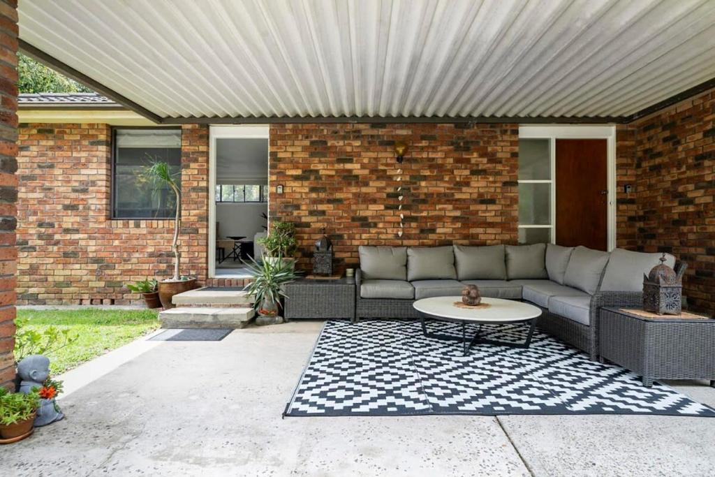 a patio with a couch and a table at Oak Retreat - Bliss by the Beach in Warriewood
