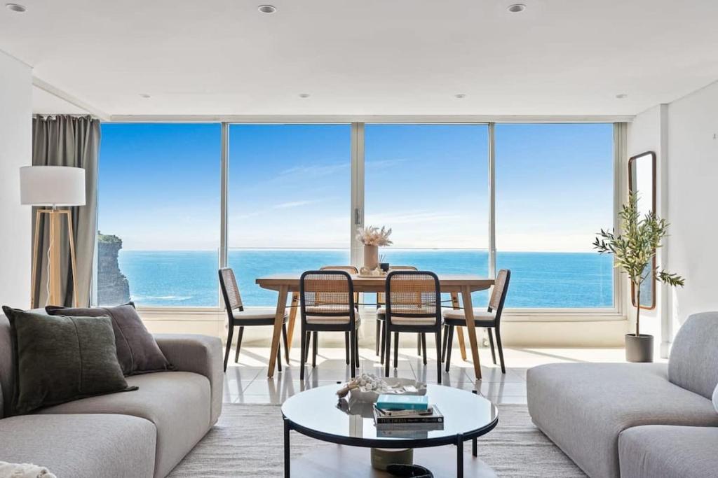 a living room with a table with a view of the ocean at Clifftop Oasis with Breathtaking Views in Sydney