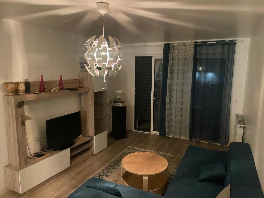un salon avec un canapé bleu et un lustre dans l'établissement Joli appart, à Marly-le-Roi