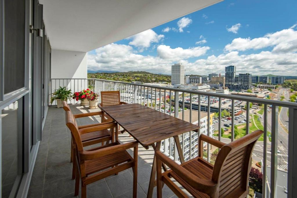 a balcony with a wooden table and chairs at Contemporary City Escape Phillip ACT in Phillip