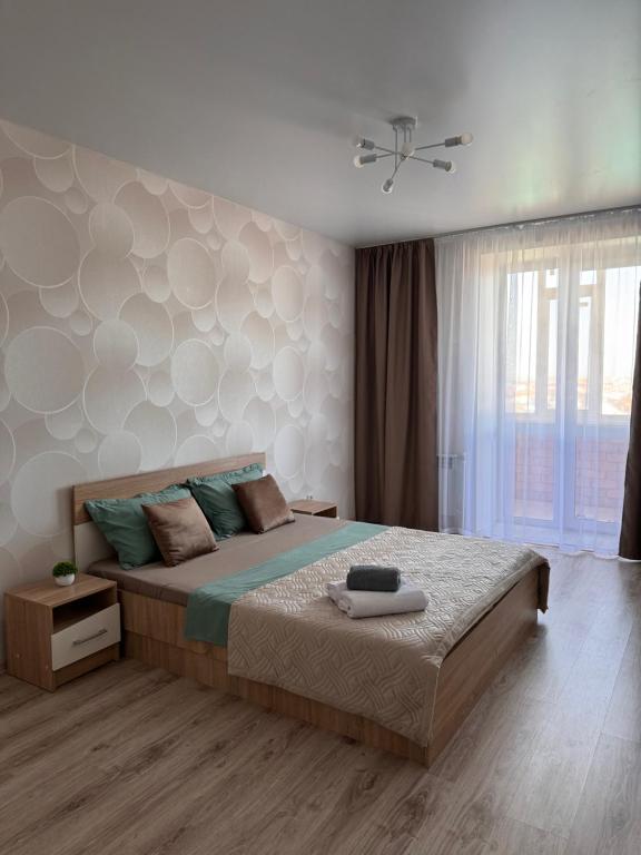 a bedroom with a large bed and a large window at 2-комнатная квартира посуточно, почасово in Kostanay