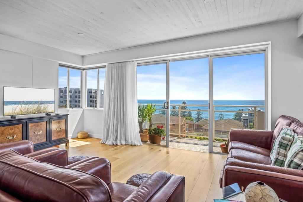 a living room with leather furniture and large windows at Spectacular Ocean View Apartment North Wollongong in Wollongong