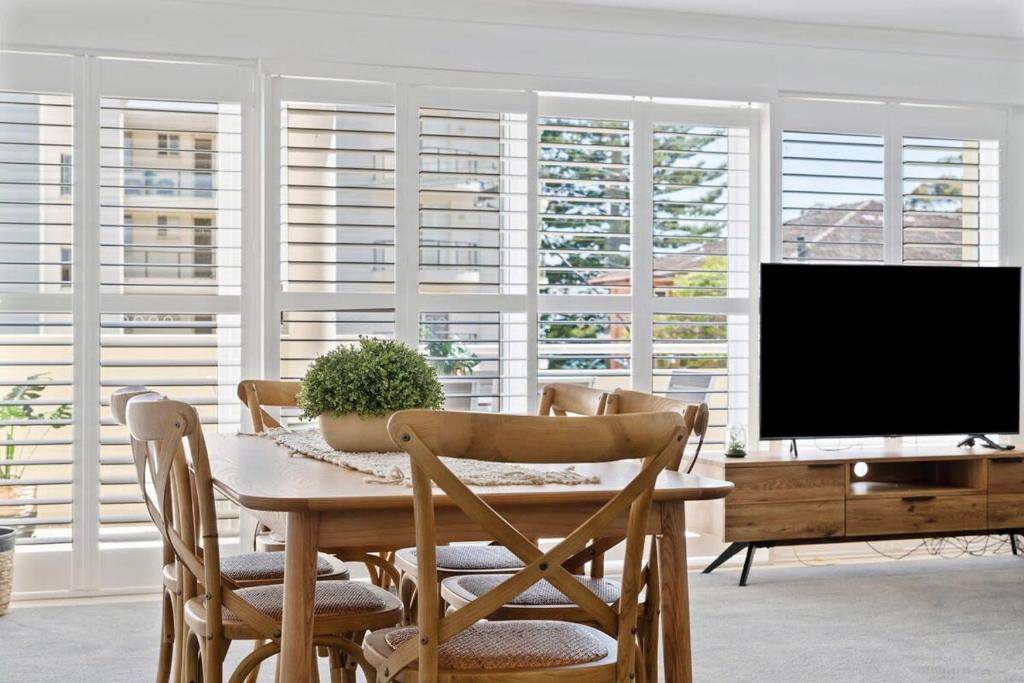 uma sala de jantar com uma televisão e uma mesa com cadeiras em Seashells Sweet Retreat - Luxury apartment em Nelson Bay