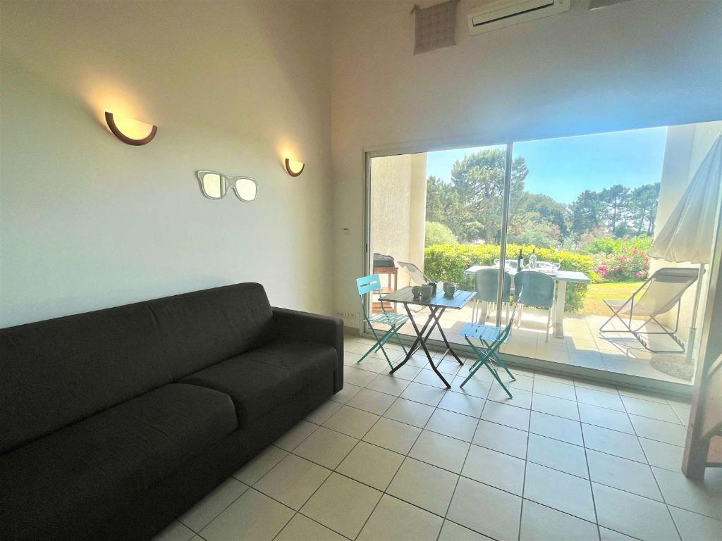 un salon avec un canapé noir et une terrasse dans l'établissement Appartement Bella Vista 302 Porticcio, à Porticcio