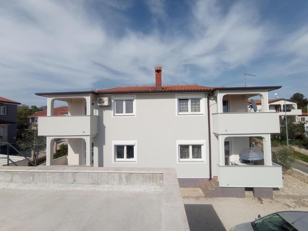 une maison blanche avec un toit rouge dans l'établissement Lara Apartments, à Umag