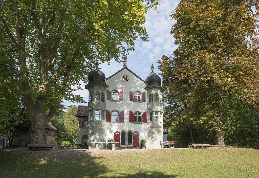 ein großes weißes Haus mit roten Türen und Bäumen in der Unterkunft Schaffhausen Youth Hostel in Schaffhausen