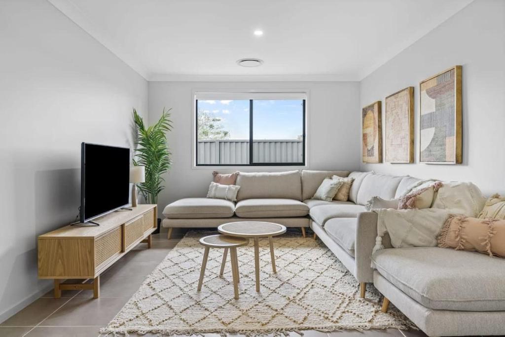 a living room with a couch and a tv at Time Out - Beautifully decorated new home in Cessnock