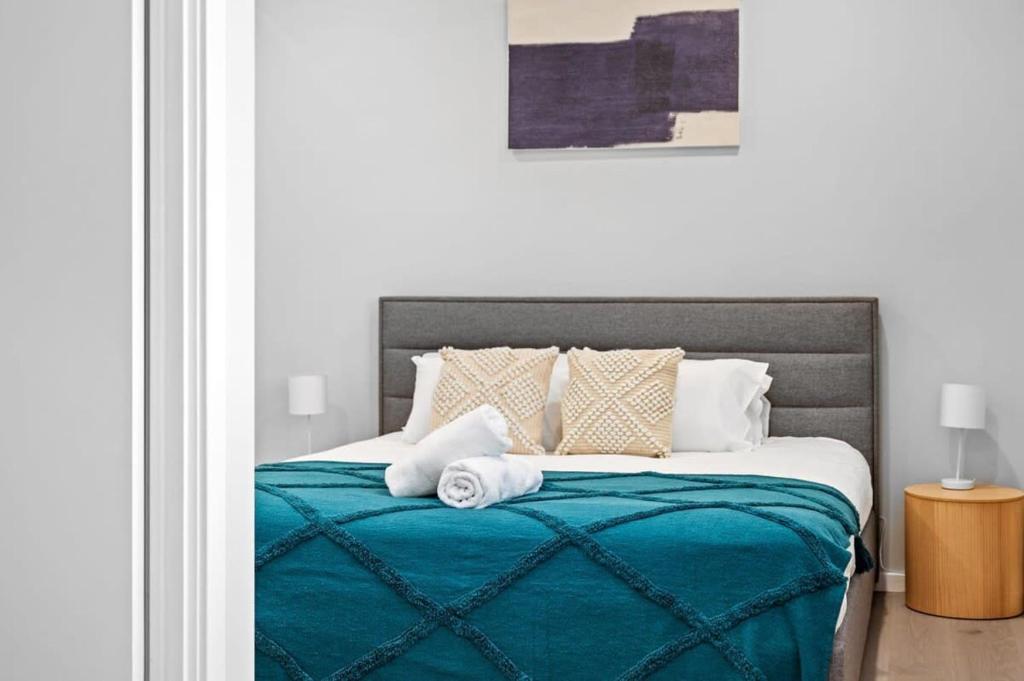 1 cama con manta azul y almohadas en Harbour-View Luxury - Herald Building Newcastle, en Newcastle