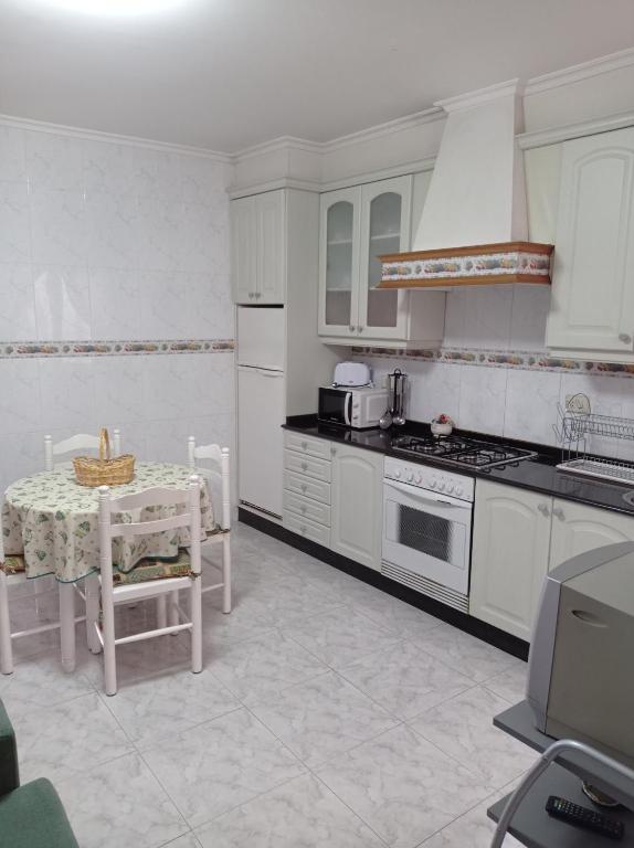 een keuken met witte apparatuur en een tafel en stoelen bij Acogedor apartamento céntrico in O Grove
