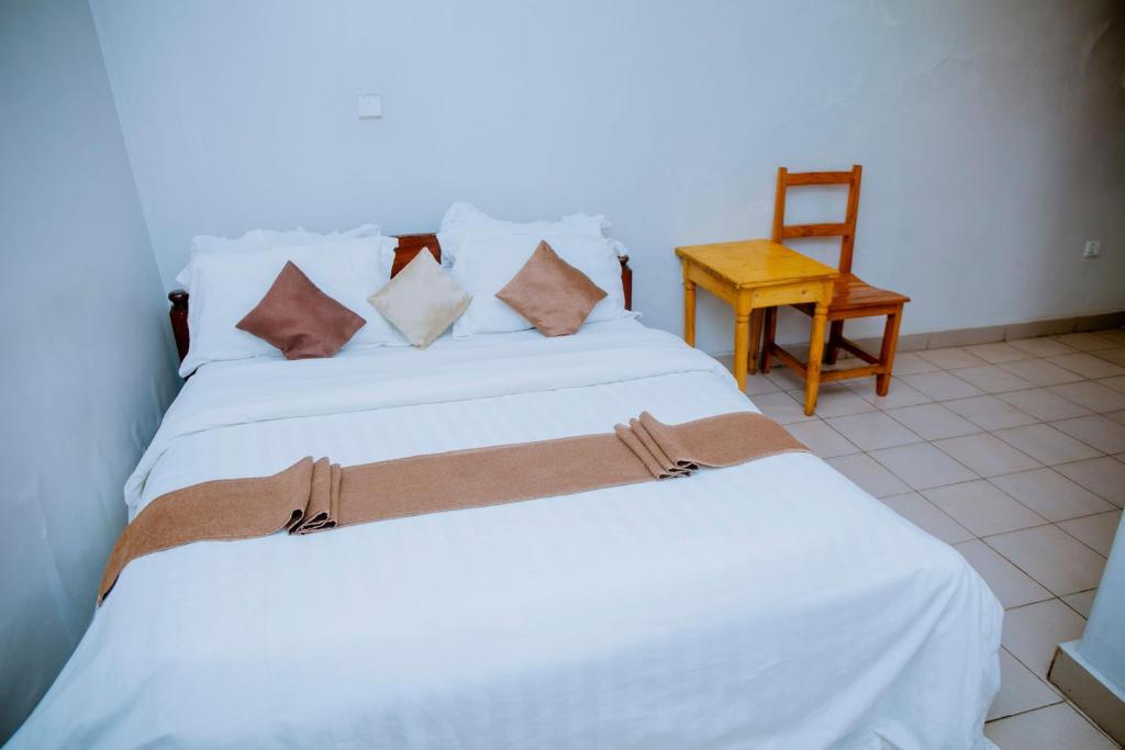 een slaapkamer met een wit bed en een stoel bij SKYLIGHT MOTEL Airport Road in Kigali