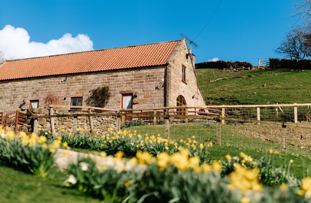 um antigo edifício de pedra com uma cerca e flores em The Arches em Westerdale