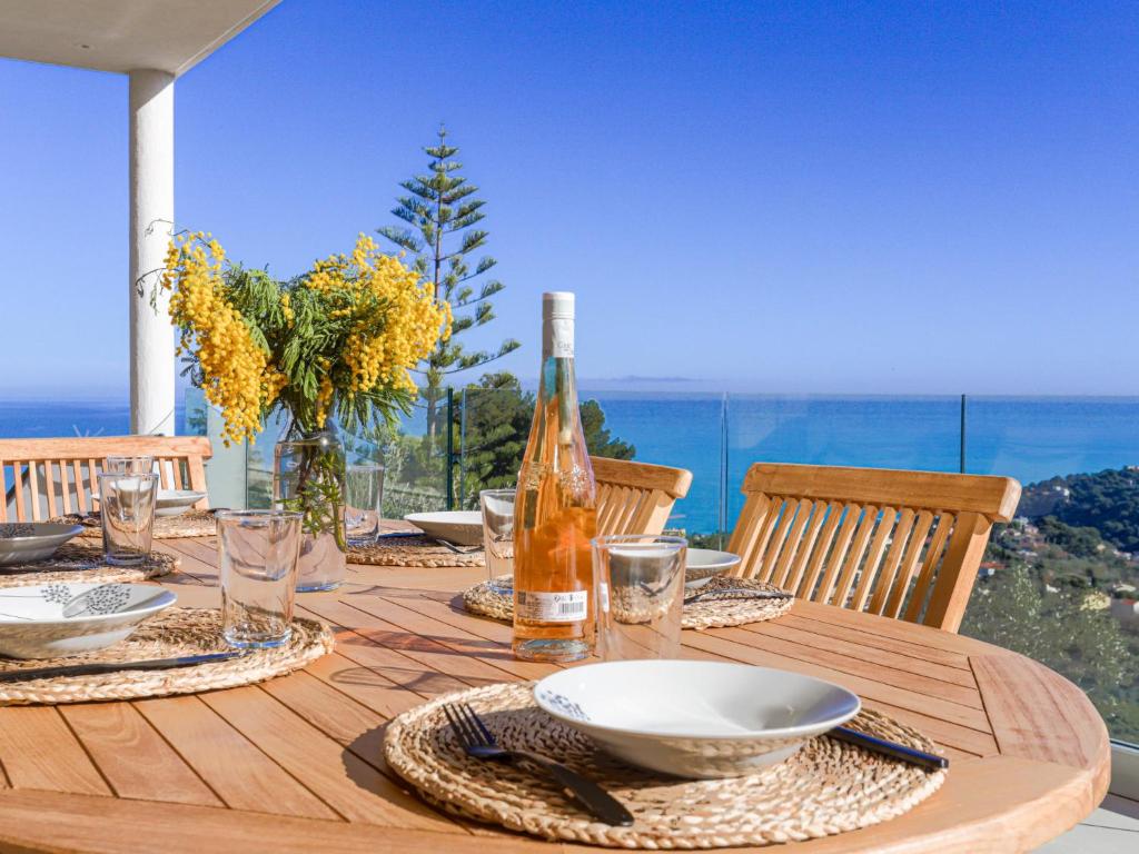 a wooden table with a bottle of wine and glasses on it at Villa La Concorde by Interhome in Roquebrune-Cap-Martin