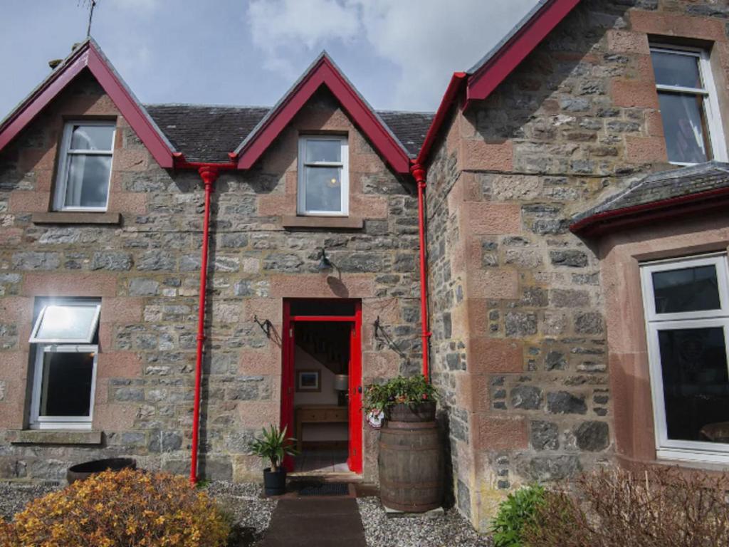 stary kamienny dom z czerwonymi drzwiami w obiekcie Holiday Home Oakdale House by Interhome w mieście Drumnadrochit