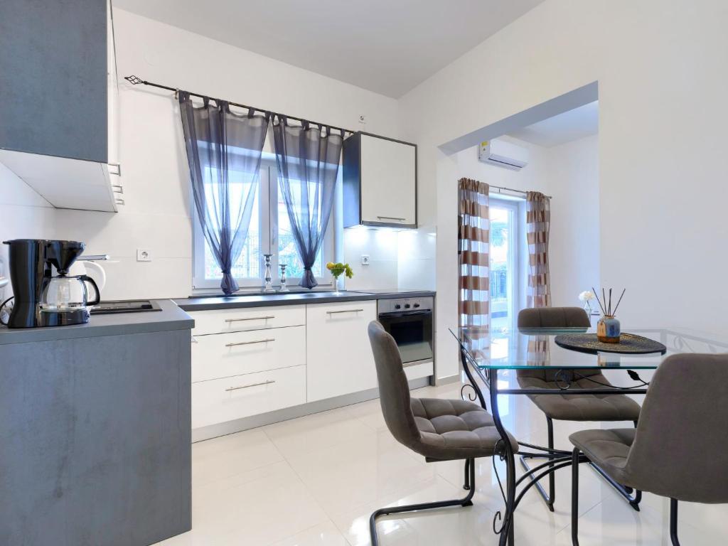 cocina con armarios blancos y mesa de cristal en Apartment Villa Amra-1 by Interhome, en Poreč