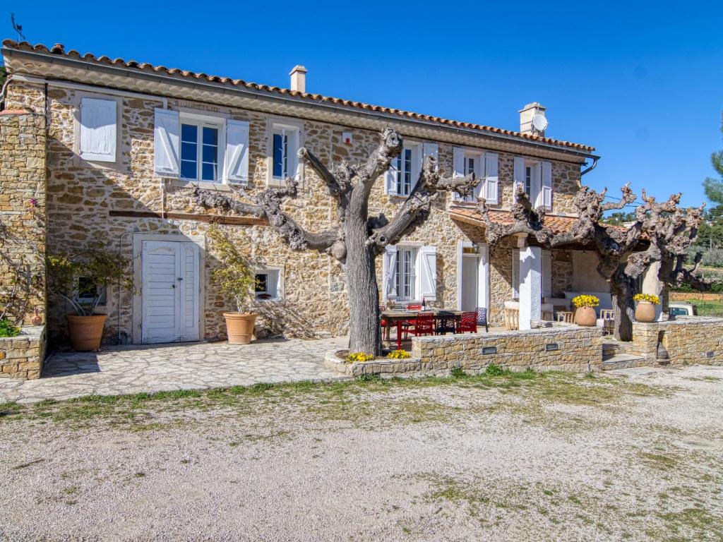een oud stenen huis met een boom ervoor bij Holiday Home La Bastide de Magdeleine by Interhome in Laouque