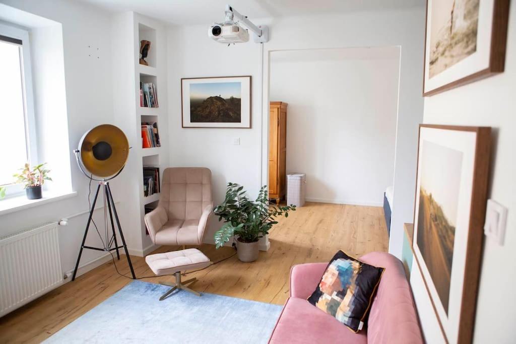 a living room with a pink couch and a chair at Studio Apartment in Warszawa Wola in Warsaw