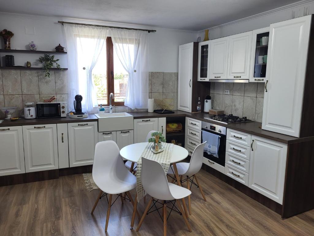 uma cozinha com armários brancos e uma mesa e cadeiras em Casa La Balauri em Drobeta-Turnu Severin