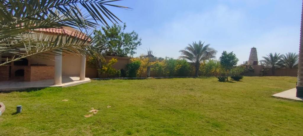 einen Garten mit grünem Rasen mit Bäumen und einem Gebäude in der Unterkunft ٦اكتوبر in Madinat as-Sadis min Uktubar