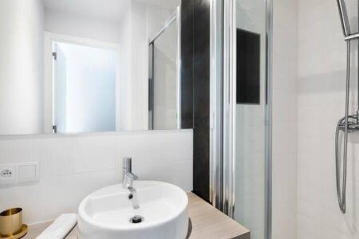 une salle de bain blanche avec un lavabo et un miroir dans l'établissement A 1 minutes du parc des expositions, à Paris
