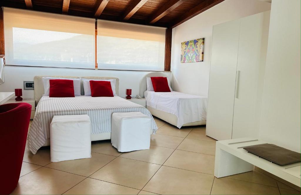 een kamer met 2 bedden en rode kussens bij Riviera Ionica in Santa Teresa di Riva